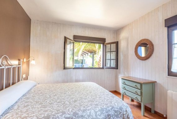 Apartamentos Habitación iluminada con cama, ventana abierta y muebles en tonos suaves.