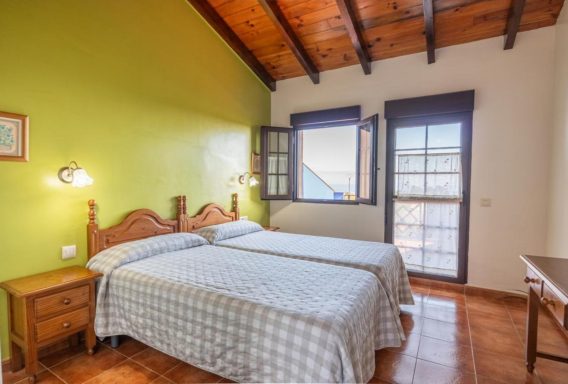 Habitaciones vistas al mar Habitación con dos camas individuales, paredes verdes y ventana con luz natural.