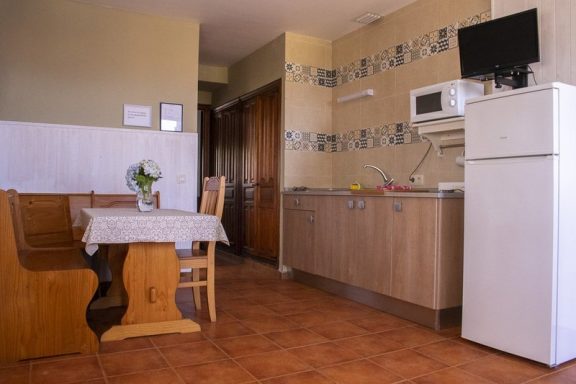 Apartamentos Cocina pequeña con mesa de madera, sillas y electrodomésticos.