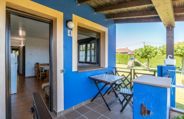 Apartamentos Terraza de una casa con mesas y sillas, rodeada de naturaleza y un ambiente tranquilo.