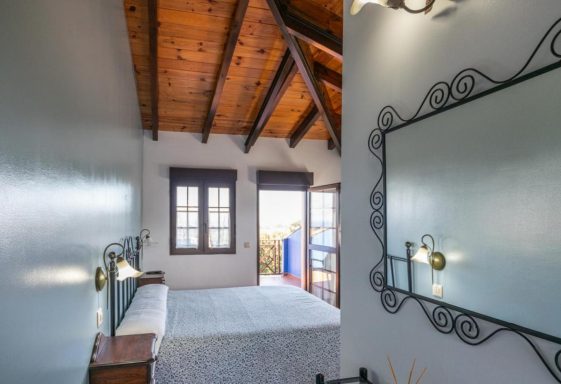 Habitaciones vistas al mar Habitación con techos de madera, cama y ventanas con vista exterior.